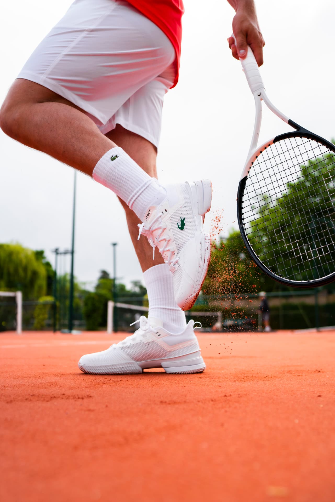 Tennis player moving on a clay court with racket in hand